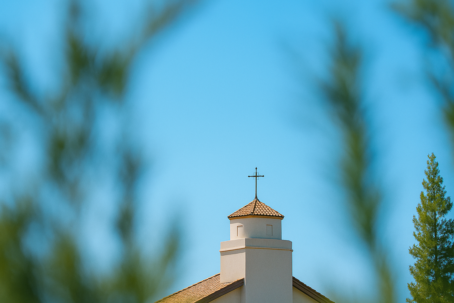 White church steeple with red tile roof and cross against bright blue sky, surrounded by lush green trees symbolizing growth and faith reaching upward